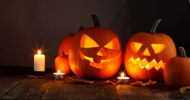 Halloween pumpkin head jack o lantern and candles on wooden background