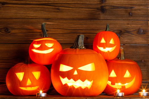 Halloween pumpkin head jack o lantern and candles on wooden background