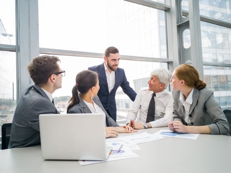 Business team sitting by the table with laptop and documents in office