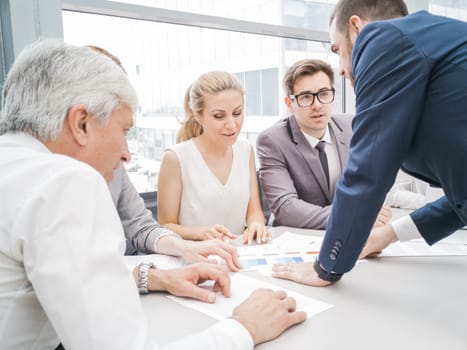 Group of business people discussing diagrams in office together