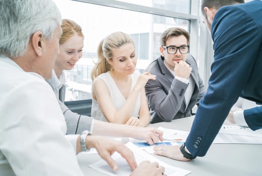 Group of business people discussing diagrams in office together
