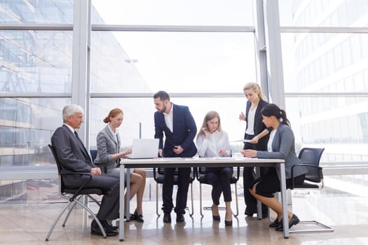 Business team sitting by the table with laptop and documents in office