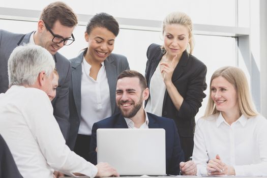 Business team sitting by the table with laptop and documents in office