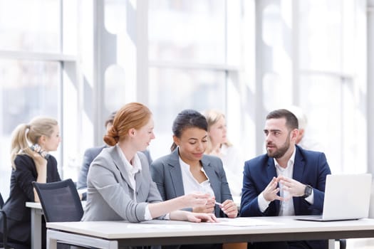 Business team sitting by the table with laptop and documents in office