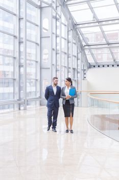 Businessman and businesswoman walk together and talk about business holding coffee in hand