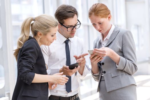 Business people with mobile phones surfing the net at break in office