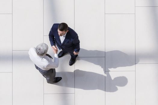 Business partners shaking hands as a symbol of unity, view from the top