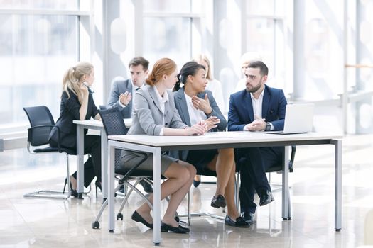 Business team sitting by the table with laptop and documents in office