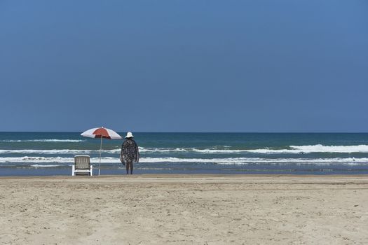 Woman Standing on the beach admiring the ocean in front of her