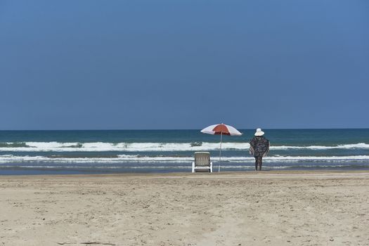 Woman Standing on the beach admiring the ocean in front of her