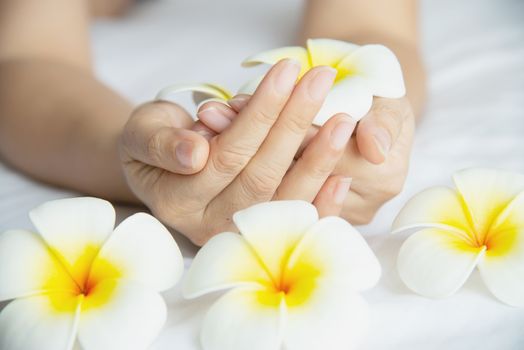 Lady hand holding beautiful white yellow plumeria flowers on white bed - people with spa flower peaceful mind concept