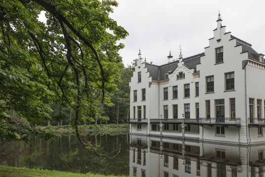 Castle Staverden reflecting in the moat and surrounded by nature trees and park