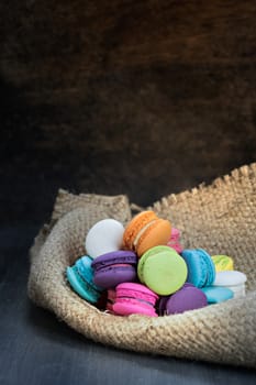 colorful of macarons on a sack over wooden table