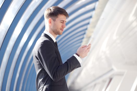 Businessman looking at his smartphone in modern building