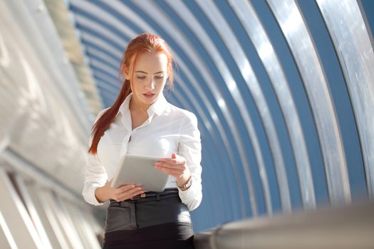 Beautiful modern businesswoman using tablet computer inside modern building