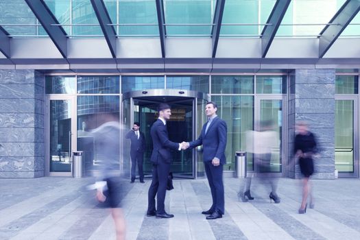 Business people shaking hands, finishing up a meeting outside office