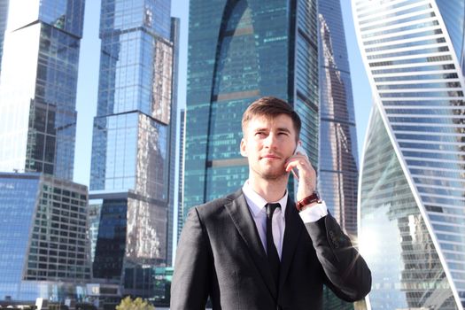 Businessman talking on the phone on skyscraper background