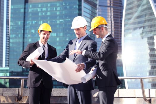 Architects with blueprint at skyscrapers background