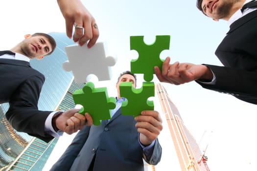 Business people assembling jigsaw puzzle near skyscrapers