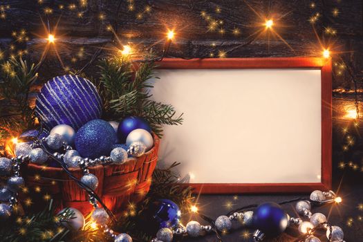 Christmas composition with a wooden frame, lights and decorations in a basket, copy space, place for text.