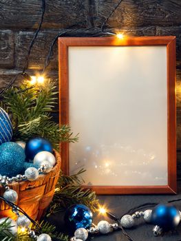 Christmas composition with a wooden frame, lights and decorations in a basket, copy space, place for text.