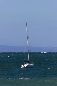 A sailing yacht at anchor in the bay just beyond the surf, Mossel Bay, South Africa