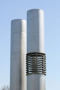 two silver-colored exhaust pipes with blue sky in the background