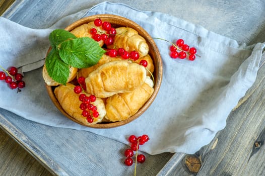 Croissants with currant berries on a wooden tray. The concept of a wholesome breakfast