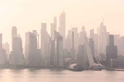 New York City midtown Manhattan skyline panorama view from Boulevard East Old Glory Park over Hudson River on a misty morning.