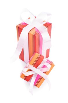Two gifts wrapped in colorful wrapping paper with white ribbons, isolated on white background.