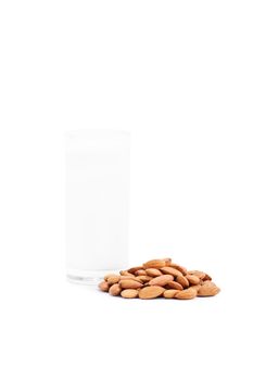 Close up shot of a glass of almond milk with a heap of almonds, isolated on white background.