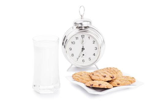 Close up shot of chocolate chip cookies on a platter with a glass of milk and alarm clock, isolated on white background. My morning and evening snack.