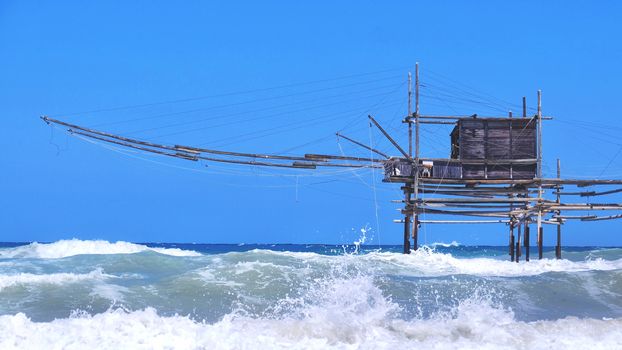 Trabocchi coast in Abruzzo with big waves on rough sea - Italy - a trabucco is an old fishing machines famous in south italy sea .