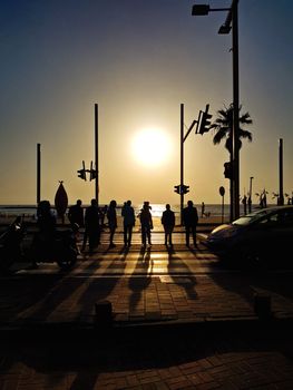 Silhouettes crossing street at sunset in Tel Aviv.