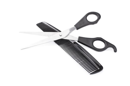 Crossed scissors and comb, isolated on white background.