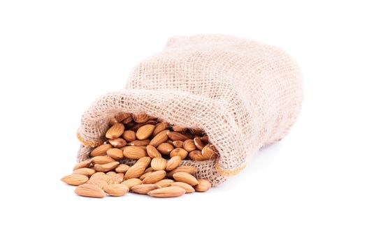 Close up shot of spilled burlap sack of almonds, isolated on white background.