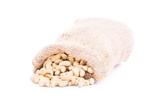 Spilled burlap sack of cashews, isolated on white background.