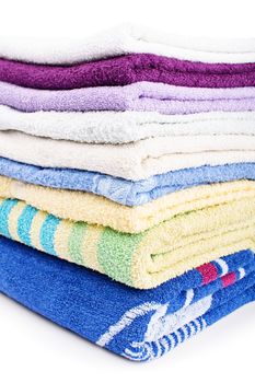 Close up shot of a pile of colorful clean bathroom towels, isolated on white background.