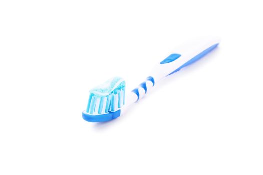 Close-up shot of a toothpaste on a blue toothbrush, isolated on white background.