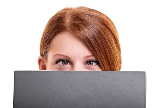 Close up shot of a young female student hiding her face behind a notebook, making funny face and crossing her eyes, isolated on white background.