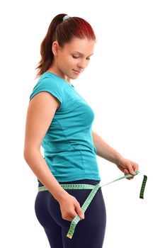 Beautiful fit young woman in sports outfit measuring her hips with a measuring tape, isolated on white background.