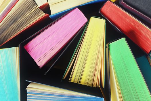 Top view of several open books with multicolored sprayed edges. 