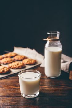 Glass of Milk with Bottle and Oatmeal Cookies on Parchment Paper. Copy Space on the Top.