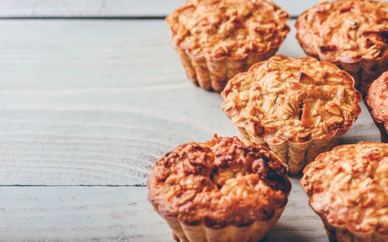 Cooked oatmeal muffins on light wooden background.