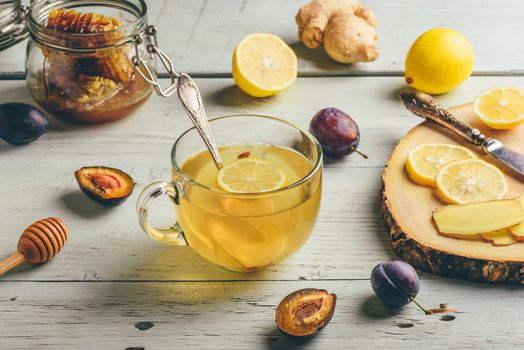 Cup of tea with lemon, honey and ginger over wooden surface