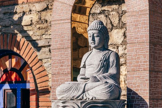 White stone statue of a Buddha on masonry background