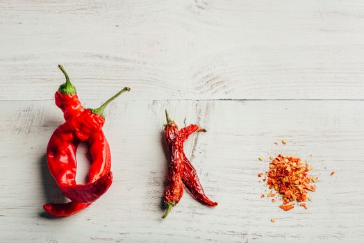 Fresh, dried and crushed red chili pepper over white wooden background.