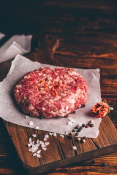 Raw Pork Patty with Spices on Cutting Board for Burger. Vertical Orientation.