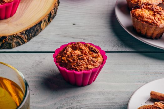 Healthy Dessert. Oatmeal muffins with cup of green tea over light wooden background.