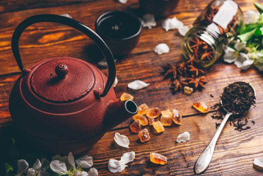 Teapot with Spoonful of Tea, Apple Flowers, Sugar and Anise Star on Wooden Table.